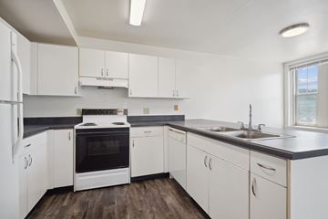 Moline apartment for rent - A kitchen with white cabinets and a black countertop.