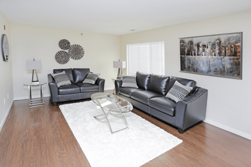 Bismarck apartment for rent - A living room with two black leather couches and a glass coffee table.