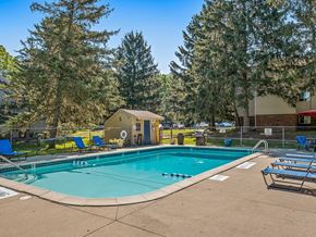 Haslett apartment for rent - A swimming pool surrounded by trees and chairs.