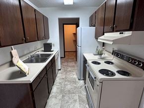 Waite Park apartment for rent - a kitchen with brown cabinets and white appliances
