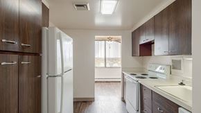 Lansing apartment for rent - A kitchen with a white refrigerator and brown cabinets.