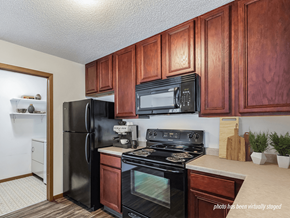 Coon Rapids apartment for rent - A kitchen with black appliances and wooden cabinets.