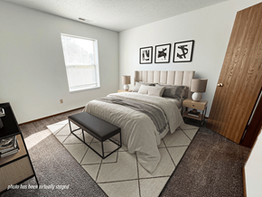 Coon Rapids apartment for rent - A bedroom with a large bed and a bench in front of it.