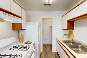Pueblo apartment for rent - A kitchen with a white gas stove and white cabinets.