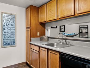 Albuquerque apartment for rent - A kitchen with wooden cabinets and a poster on the wall with positive words.