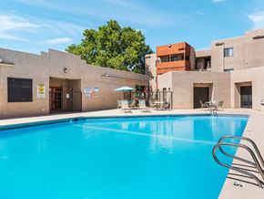 Albuquerque apartment for rent - A swimming pool in front of a building with a blue sky in the background.