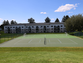 Fitchburg apartment for rent - A tennis court is located in front of a large building.