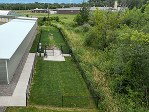 St. Cloud apartment for rent - A green fenced dog park area with a small building to the left.