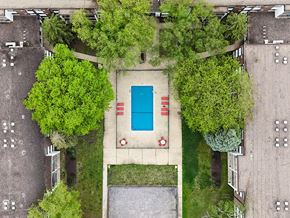 Rochester apartment for rent - A pool surrounded by trees and grass in a parking lot.