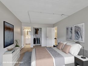 Rochester apartment for rent - A bedroom with a large bed, a wardrobe, and a painting on the wall.