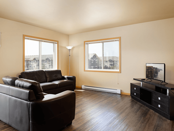 Watford City apartment for rent - A living room with black leather couches and a wooden floor.
