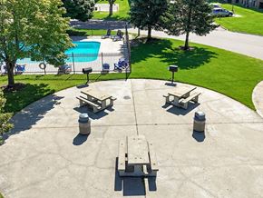 Waite Park apartment for rent - A concrete patio with four benches and a pool in the background.