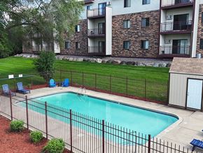 Saint Cloud apartment for rent - A pool surrounded by a black fence and a building in the background.