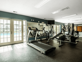 Omaha apartment for rent - a gym with cardio equipment and a pool in the background