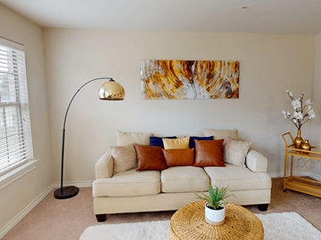Abilene apartment for rent - A living room with a white couch, a lamp, and a painting on the wall.