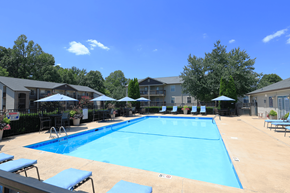 Burlington apartment for rent - A large blue swimming pool surrounded by sun loungers and umbrellas.