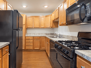 Mishawaka townhouse for rent - A kitchen with black appliances and wooden cabinets.