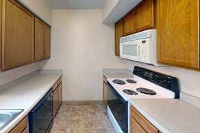 Wichita townhouse for rent - A kitchen with a white microwave above a stove and a sink to the left.