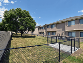 Derby apartment for rent - A black fence surrounds a grassy area in front of apartment buildings.