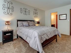 Burnsville apartment for rent - A bedroom with a large bed and a nightstand with a lamp.