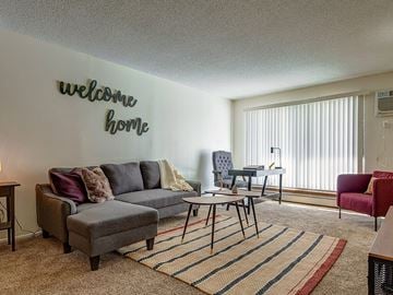 Burnsville apartment for rent - A living room with a grey sofa and a welcome home sign.