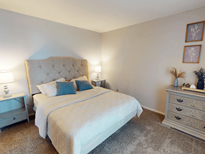 St. Louis apartment for rent - A bedroom with a large bed and a nightstand with a lamp.