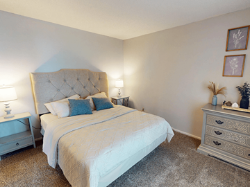 St. Louis apartment for rent - A bedroom with a large bed and a nightstand with a lamp.