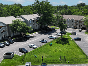 St. Louis apartment for rent - A dog park near a parking lot with cars and apartment buildings in the background.