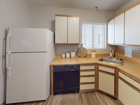 St. Louis apartment for rent - A white refrigerator stands in a kitchen with wooden cabinets and a black dishwasher.