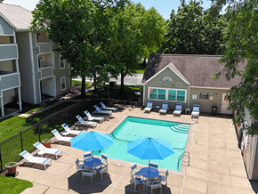St. Louis apartment for rent - A pool surrounded by chairs and umbrellas with trees and a building in the background.
