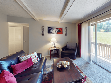 St. Louis apartment for rent - A living room with a black couch and a table with a bowl of fruit on it.