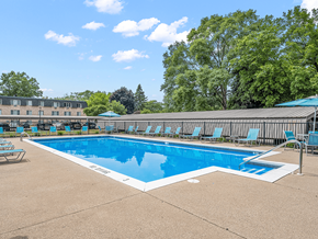 Muskegon apartment for rent - a swimming pool with chaise lounge chairs and trees in the background