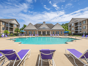 Fayetteville apartment for rent - A large swimming pool surrounded by purple lounge chairs in front of apartment buildings.
