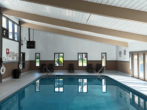 Albuquerque apartment for rent - A large indoor swimming pool with lane dividers and a few chairs.