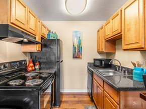 Albuquerque apartment for rent - A kitchen with wooden cabinets and a black stove.