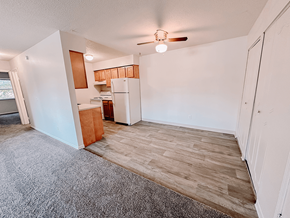 Newark apartment for rent - an empty living room with a kitchen and a ceiling fan
