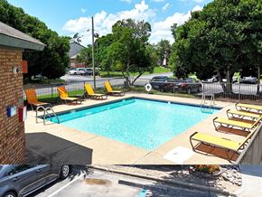 Little Rock apartment for rent - A pool with yellow chairs and a black car in the background.