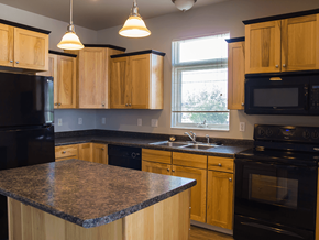 Minot apartment for rent - a kitchen with wooden cabinets and black appliances