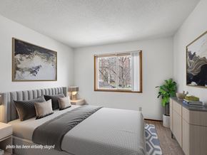 Rochester townhouse for rent - A bedroom with a large bed and a painting on the wall.