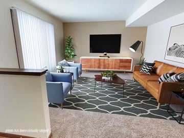 Rochester townhouse for rent - A living room with a blue chair, a brown couch, and a television on the wall.
