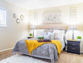 Omaha townhouse for rent - a bedroom with white walls and a yellow blanket on the bed