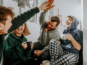 Chillicothe apartment for rent - Four people in pajamas are sitting on a couch, laughing and holding mugs.