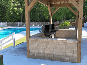 Fayetteville apartment for rent - A wooden pergola with a grill is situated next to a pool.
