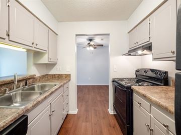 Fayetteville apartment for rent - A kitchen with white cabinets and a black stove top oven.