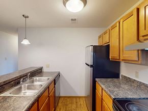 Maryland Heights apartment for rent - A kitchen with a black refrigerator and wooden cabinets.
