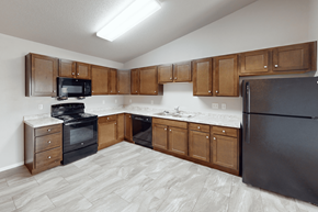 Williston apartment for rent - A kitchen with wooden cabinets and black appliances.