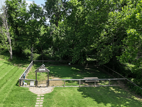 Mehlville townhouse for rent - A small gazebo is surrounded by a fence and a picnic table in a grassy area.
