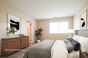 Omaha triplex for rent - A bedroom with a bed, dresser, and window.