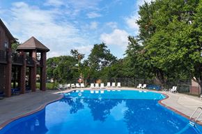 Omaha triplex for rent - A large blue swimming pool with white lounge chairs and a gazebo in the background.
