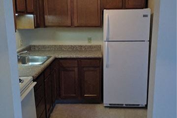 Sandusky apartment for rent - A white refrigerator in a kitchen with brown cabinets.